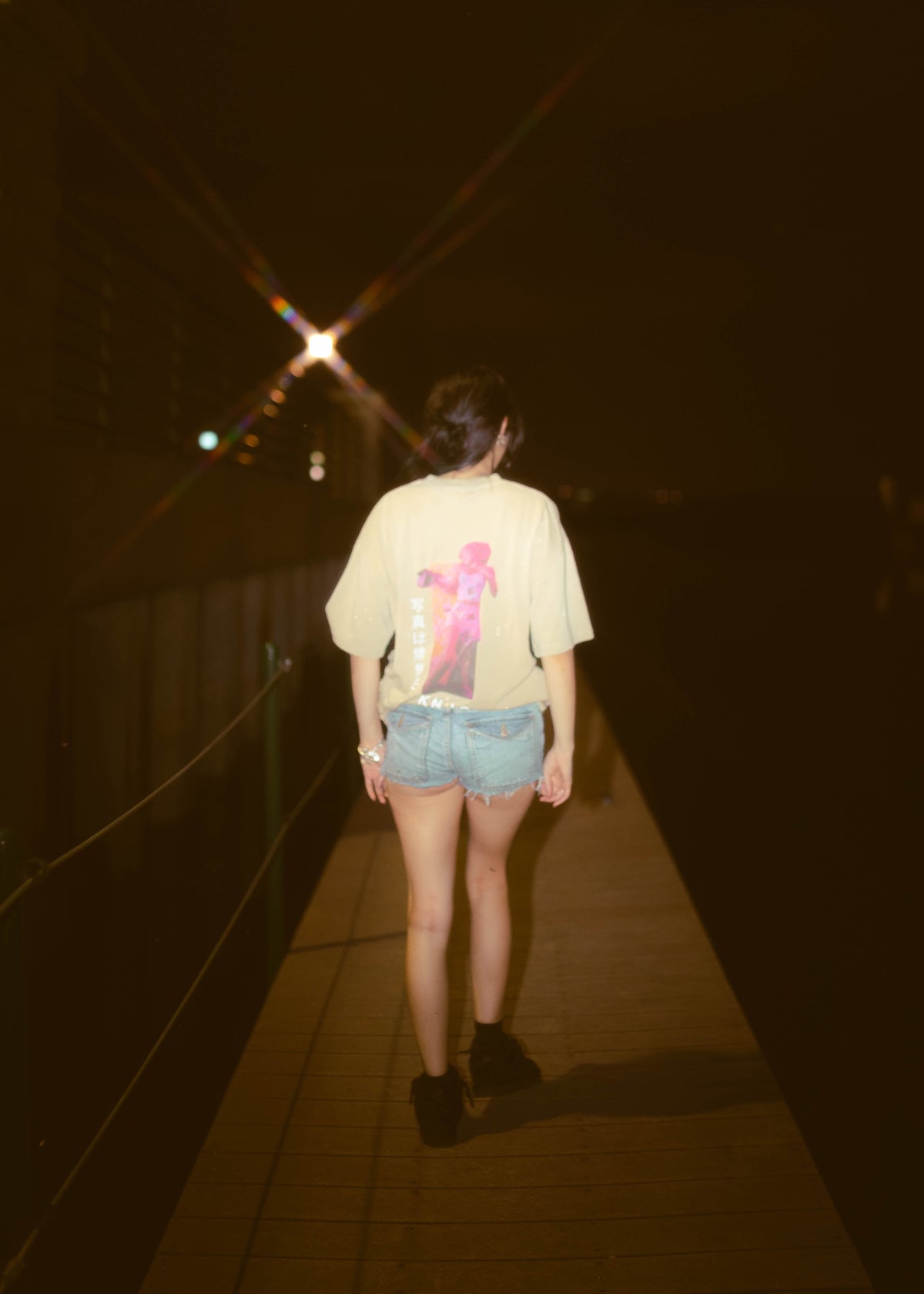 KNJO graphic T-shirt worn with denim shorts during a nighttime streetwear photoshoot